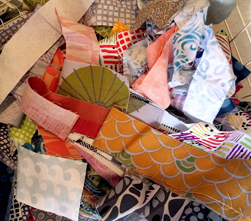 Scraps of colorful printed fabrics ready to go into the quilt